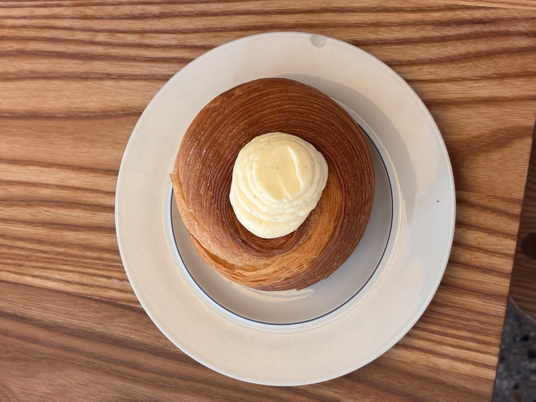 A cardamom bun with cream on a white plate
