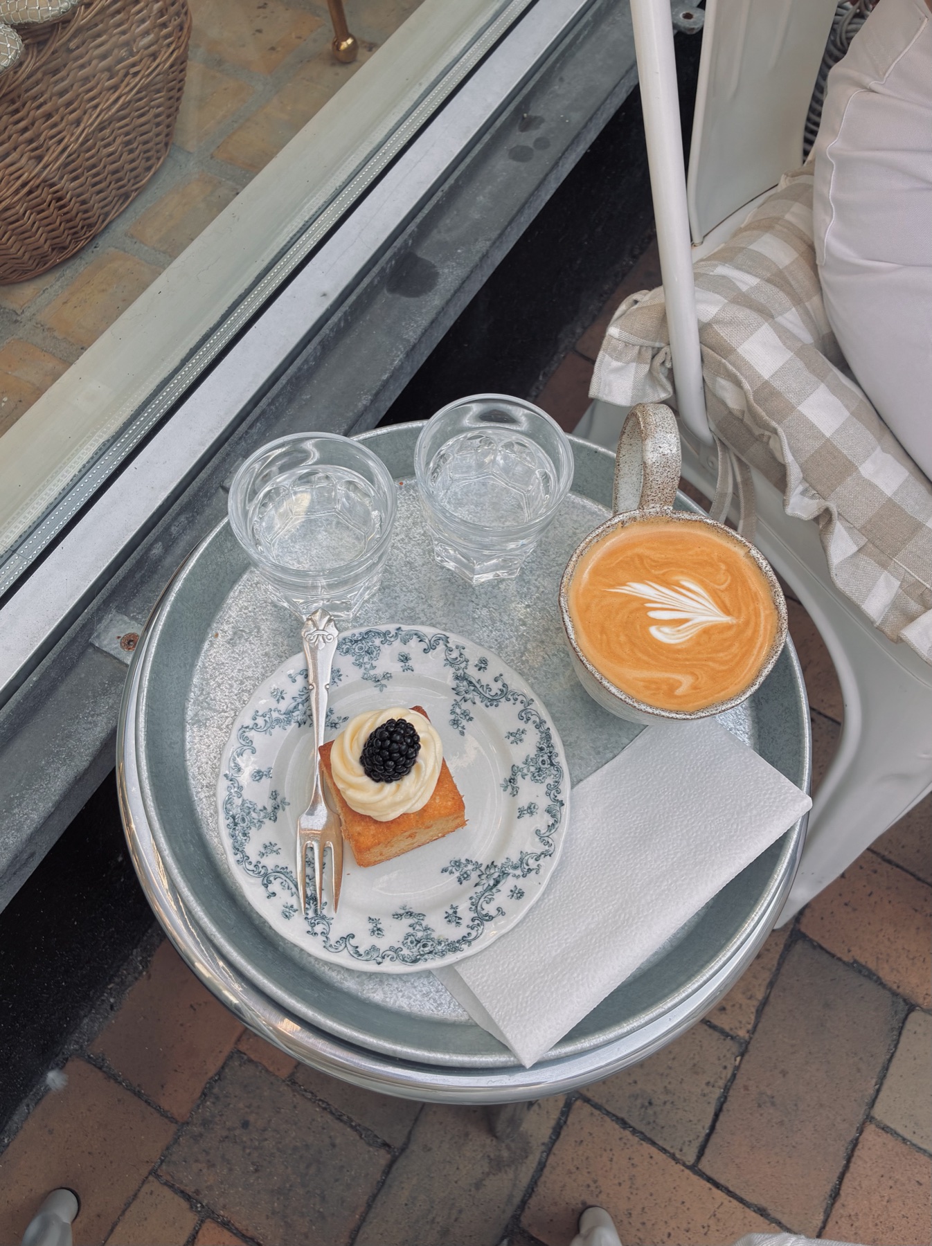 Vanilla cake with mascarpone and blackberry on a floral plate, with a latte