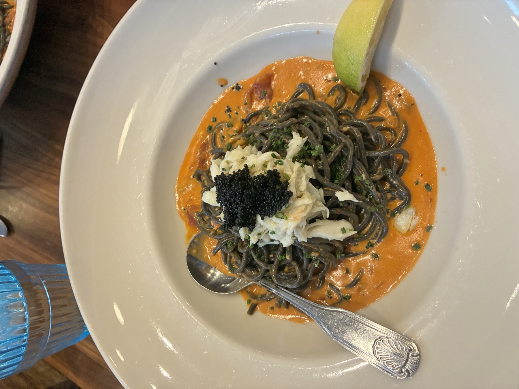 Squid ink pasta with crab and caviar in a white bowl